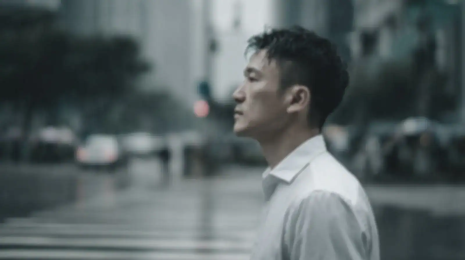 一位台灣白領在陰雨的十字路口若有所思——情緒化投資決策後的落寞與茫然